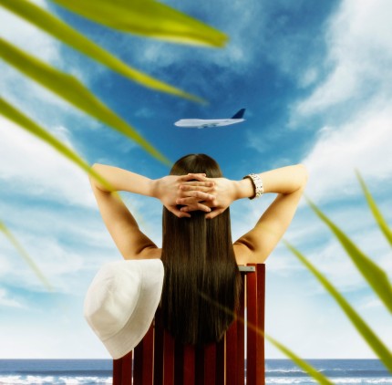 Young woman watching airplane fly by from tropical beach